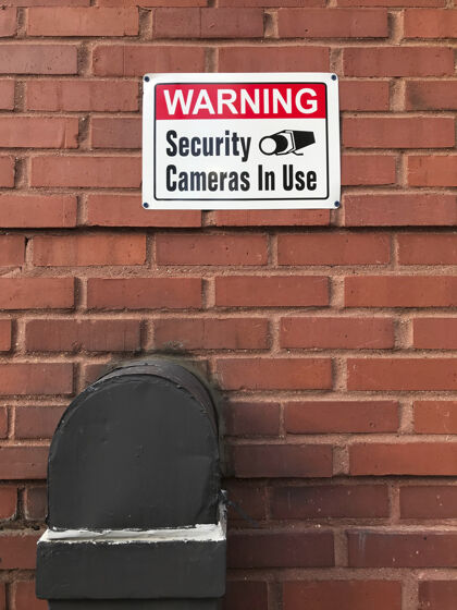 监视砖墙上的警告安全摄像头正在使用保护摄像头警告