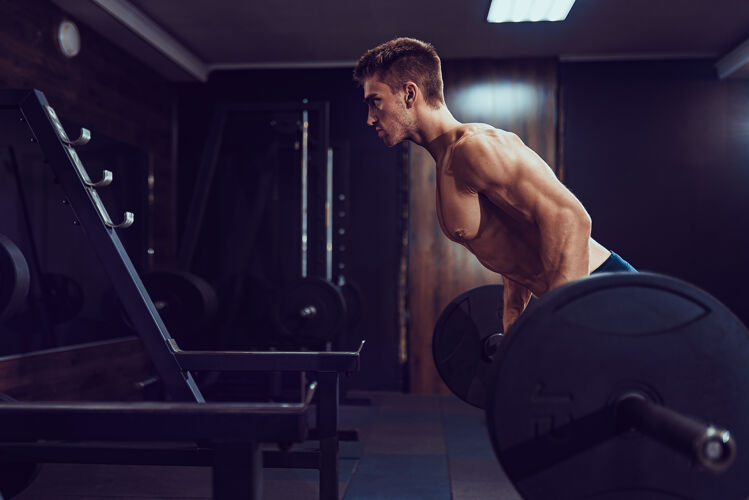 抱持为背部做重量级运动的男人痛苦与收获杠铃训练健身