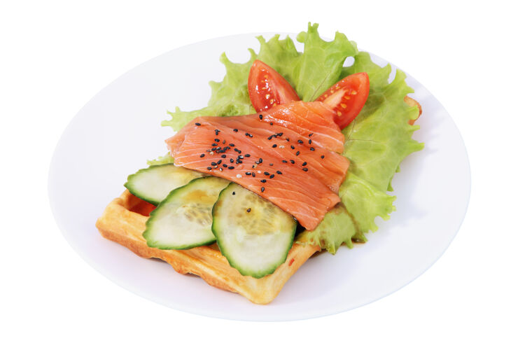片比利时华夫饼配腌鲑鱼片 西红柿 黄瓜和莴苣叶 白色背景上的独立图像盘子自制的叶子