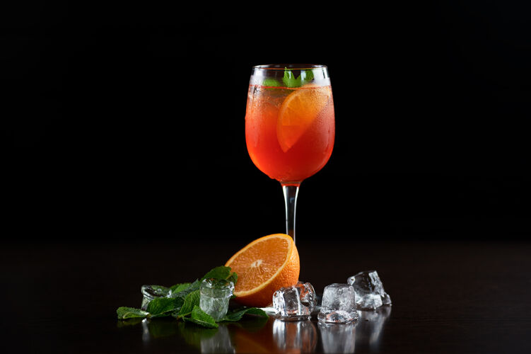 明亮精致的组合 高高的水晶鸡尾酒杯 冷饮 橙子片 新鲜的绿薄荷叶和透明的冰块热带成分透明