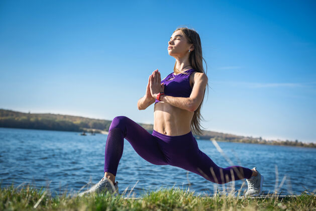 力量运动型的年轻女子白天在湖边做健身操手臂物理锻炼
