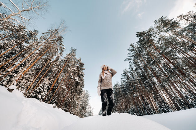雪冬天 一个穿着毛衣和手套的女孩站在被雪覆盖的背景上霜冻森林自然