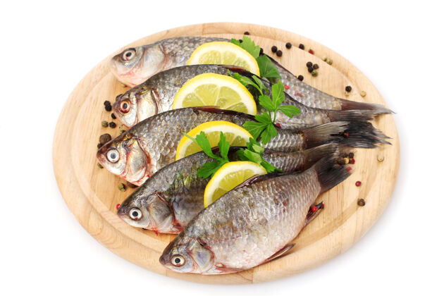 皮肤新鲜的鱼与柠檬 欧芹和香料在木制砧板隔离在白色生的鱼自然