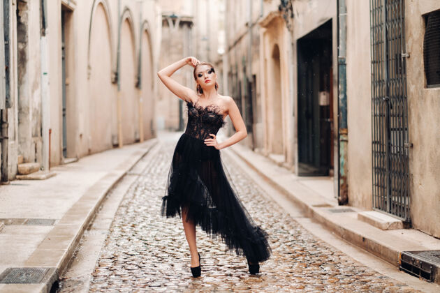 老城区一位身着黑色婚纱的时尚新娘在法国古城阿维尼翁摆出姿势穿着漂亮的黑色连衣裙的模特在普罗旺斯拍照生活方式慢黑裙