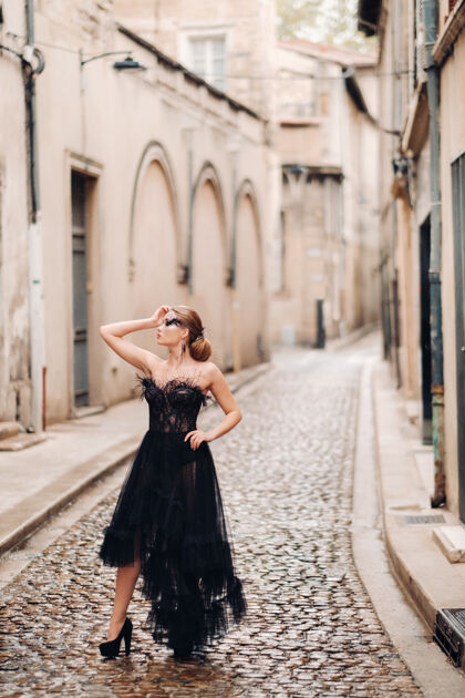 专业一位身着黑色婚纱的时尚新娘在法国古城阿维尼翁摆出姿势穿着漂亮的黑色连衣裙的模特在普罗旺斯拍照生活方式石头城轻巧