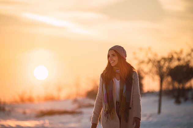 日落夕阳时分 冬日乡间 一身暖洋洋的快乐少女 在新鲜的白雪上漫步和谐年轻孤独