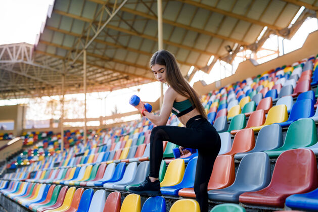 女性夏天 穿着运动服的年轻漂亮女孩在城市体育馆里练习哑铃运动理念健身户外公园