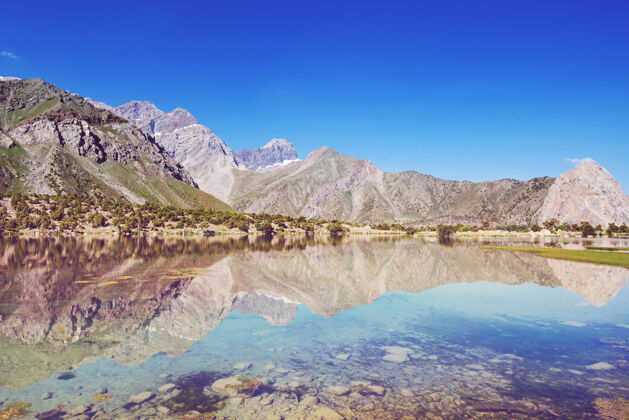 全景美丽宁静的湖泊在芬斯山脉（帕米尔的分支）在塔吉克斯坦倒影自然风景