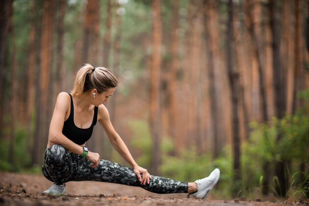 健康在松林里慢跑的年轻女子在森林里锻炼的年轻女子天然森林之光休闲站立慢跑
