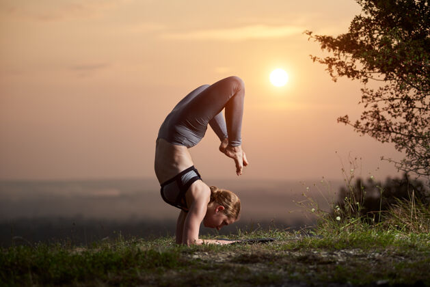 女性日落时分在户外练瑜伽的年轻女子形状活跃和谐