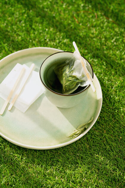 茶包柠檬马鞭草茶放在杯子里 用手工制作的茶包放在绿草上舒适的概念闭合自然光秋天柑橘食物