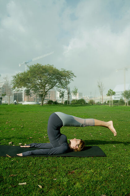 健康在公园里用瑜伽垫做瑜伽 伸展运动 锻炼的年轻女子天生的瑜伽初学者姿势医疗理念女人保健活跃