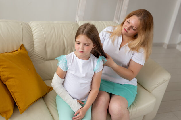 女人手臂骨折的孩子和石膏花时间在家里与母亲儿童疾病 积极的意外不幸骨折