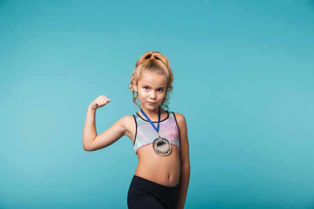 参与快乐的小运动女孩 戴着金牌 庆祝战胜蓝墙荣誉成功地点