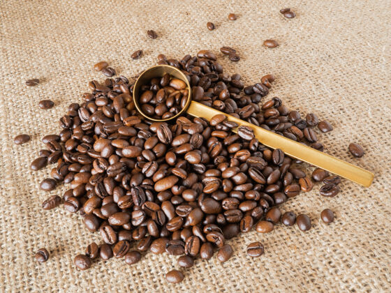质地咖啡豆与黄金测量勺和量杯亚麻质地的背景亚麻质地马克杯