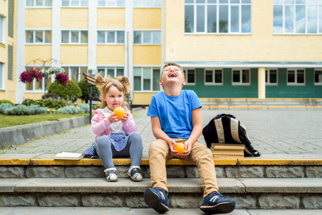 一起快乐的孩子们白天在校园里玩耍时间学校早餐 水果和果汁.stack教科书 书快乐友好的兄弟姐妹微笑教育玩耍