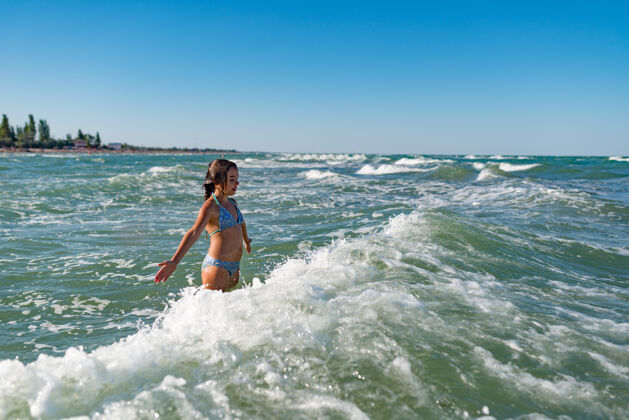 飞溅在一个阳光明媚温暖的夏日 活泼快乐的小女孩在喧闹的海浪中嬉戏梦想想象风