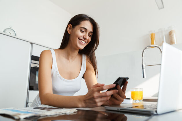 饮料健康的女人每天早上都站在厨房里用手机聊天肖像成人应用程序