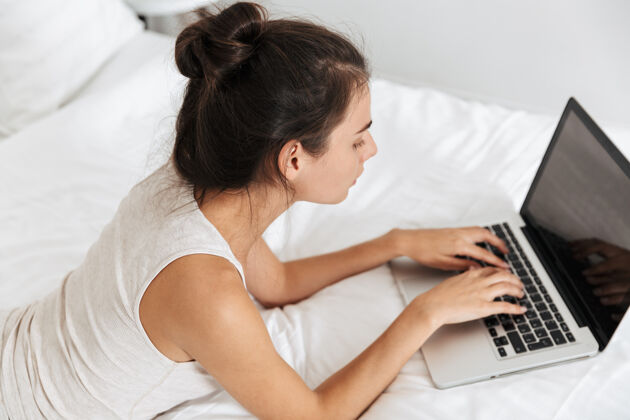 女士美丽的年轻女子在家里的床上休息 使用笔记本电脑购物活动放松