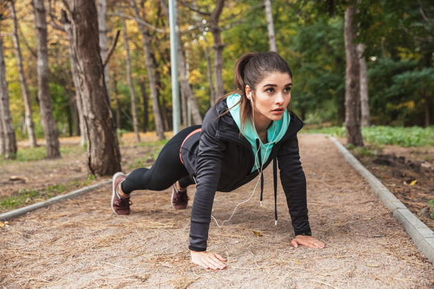活动微笑的年轻健身女孩在公园里做运动 铺板户外平板减肥