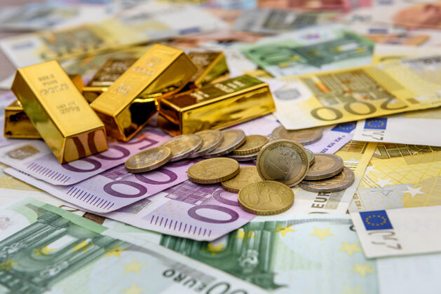 珍贵以欧元纸币为背景的金块和欧元硬币罚款金融锭