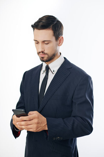 企业家穿西装的成功严肃的年轻企业家在智能手机上阅读同事的短信年轻人职业移动