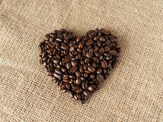 堆爱形状咖啡豆亚麻质地的背景早晨自然烤