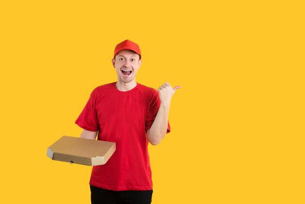 男性快乐的披萨送货员穿着黄色的红色制服帽子送货持有