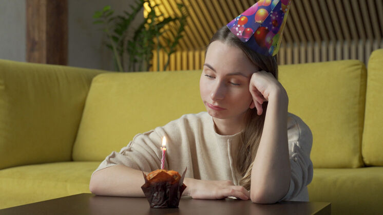 悲伤一个悲伤女孩的画像 拿着一块蛋糕和一支蜡烛 女孩吹灭了蜡烛痛苦火焰生日蛋糕