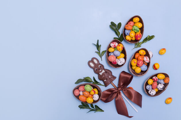 节日蓝色桌子上的复活节巧克力蛋和兔子邦邦装饰糖果