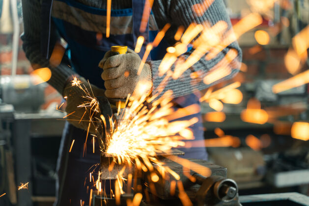 技术穿着特殊衣服和护目镜的锁匠在工厂工作生产.金属用角磨机加工切割车间角钢