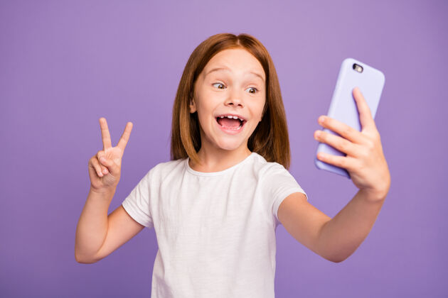 显示搞笑的小女士拿着电话自拍展示v字标志的照片手机女孩年轻