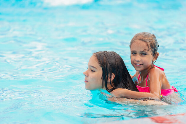 水滴在一个阳光明媚的夏日 两个可爱的小姐妹在游泳池里游泳水游泳快乐的人