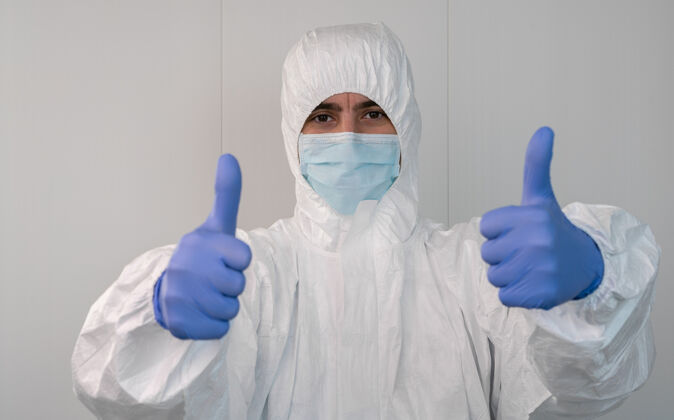 阳性特写镜头：一个穿着防护服的护士用手做着竖起大拇指的手势冠状病毒大流行 冠状病毒19医院里的医护人员带着ppe手套疾病护士