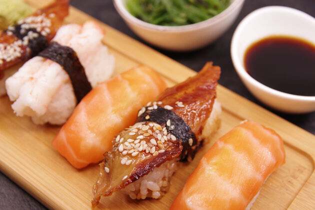 托盘木盘上的日本寿司食物 配生姜 酱油和海藻沙拉三文鱼尼吉里 虾尼吉里 乌纳吉尼吉里菜肴餐开胃菜