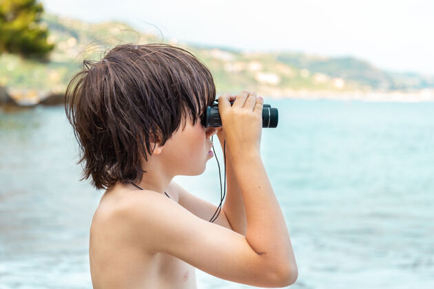 手表一个小男孩呆在海边的海滩上 用望远镜看东西距离自然探索