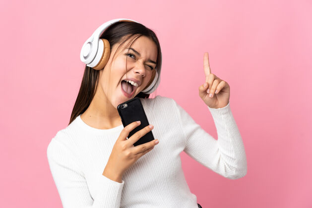 电话十几岁的女孩在蓝色的手机上听音乐 唱歌女人科技青少年