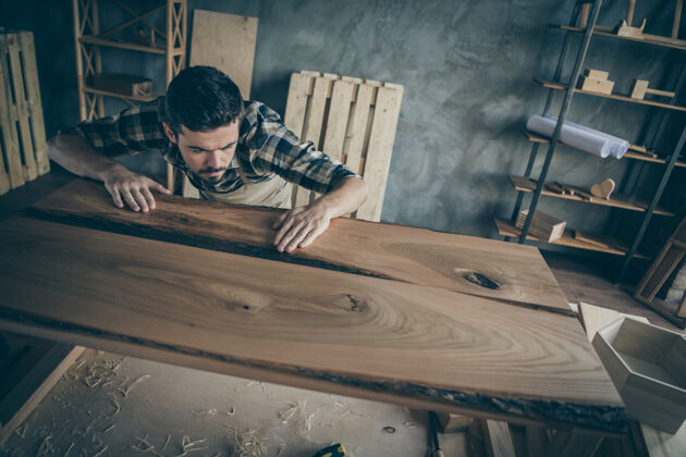 木板上面的高角度集中工头工人检查他如何顺利完成修复板表穿格子格子衬衫在家里车库工作细木工质量
