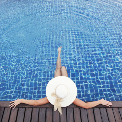 太阳帽戴帽子的女人在泳池边放松晒黑游泳池泳池边