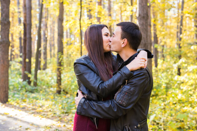 九月爱 关系 家庭和人的概念-男人亲吻他的妻子在秋季公园隐藏混合家庭