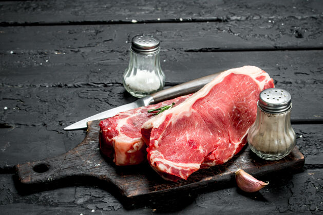 木材黑乡村桌上放着带香料和盐的生牛排蛋白质红小牛肉
