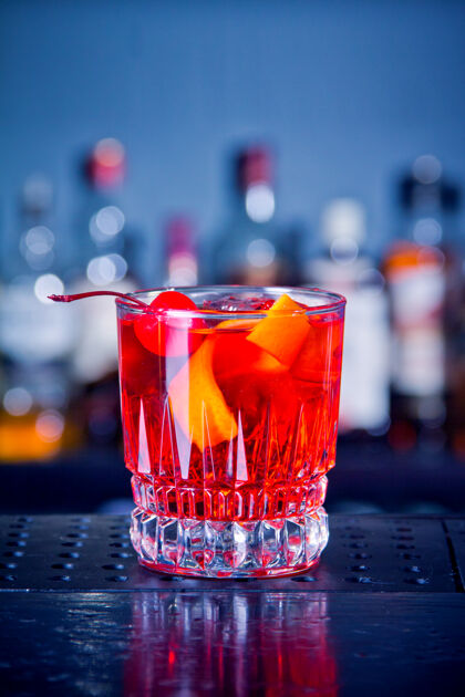 鸡尾酒在酒吧的木桌上放着樱桃和橘子皮的玻璃罐里的红色饮料鸡尾酒提神水樱桃