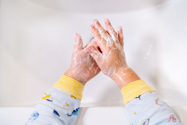 无辜孩子们穿着睡衣的手在浴室水槽里用大量泡沫洗手的俯视图浴室护理水龙头