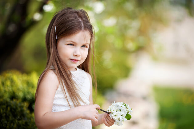 花美丽微笑的小女孩穿着奶油色的裙子 映衬着夏日公园的绿色美丽微笑年轻