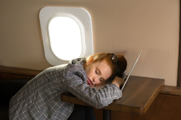 舒适红发美女坐商务舱飞机 睡在笔记本电脑上交通肖像秘书