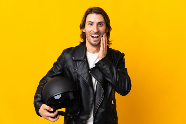 摩托车手一个戴着摩托车头盔的男人被隔离在黄色的墙上 脸上露出惊讶和震惊的表情惊喜担心手势
