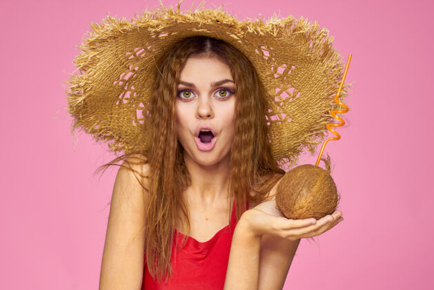 黑发戴着草帽的椰子鸡尾酒的女人异国情调的度假夏日粉色的墙壁性感季节欢呼