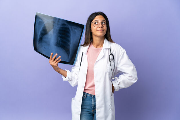 成人年轻的女医生拿着X光片抬头看护理人专业