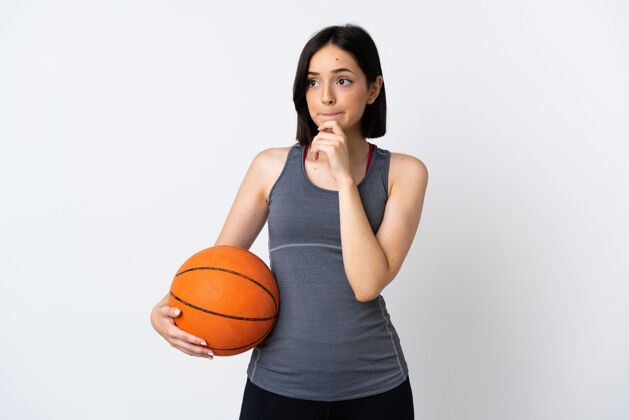 思想打篮球的年轻女子孤零零地站在白墙上 心中充满疑惑和思考健身身体选择