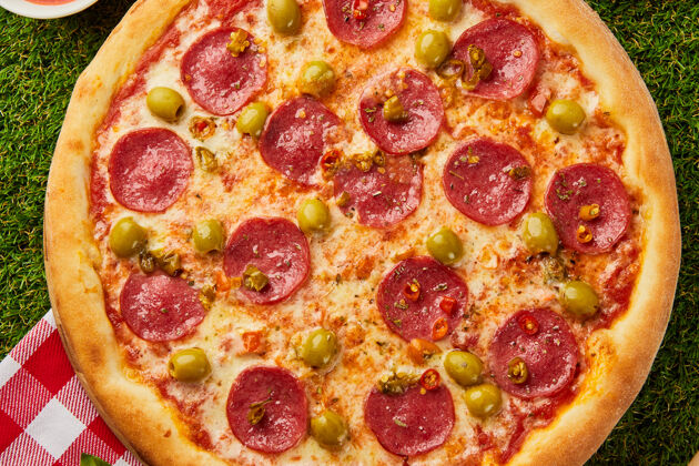 马苏里拉传统的意大利披萨意大利香肠配意大利香肠 意大利马苏里拉 橄榄和罗勒 背景是绿草洋葱肉意大利